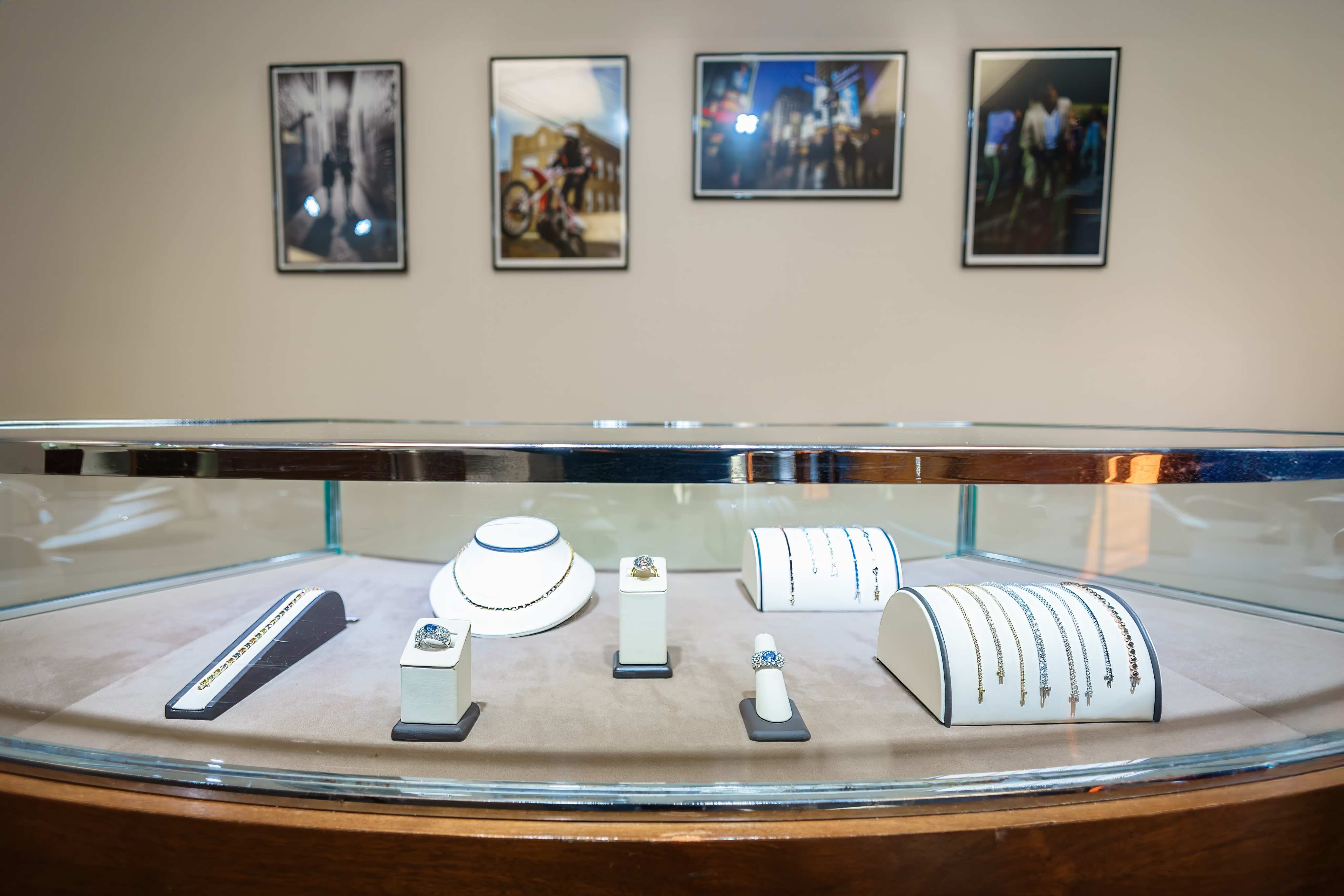 Jewelry display case with rings and tennis bracelets, framed photography on the wall behind