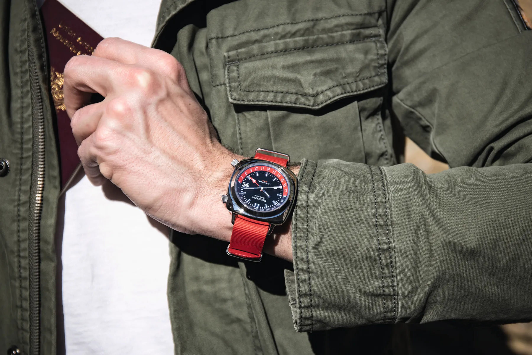 A Briston watch on a red strap worn at the wrist