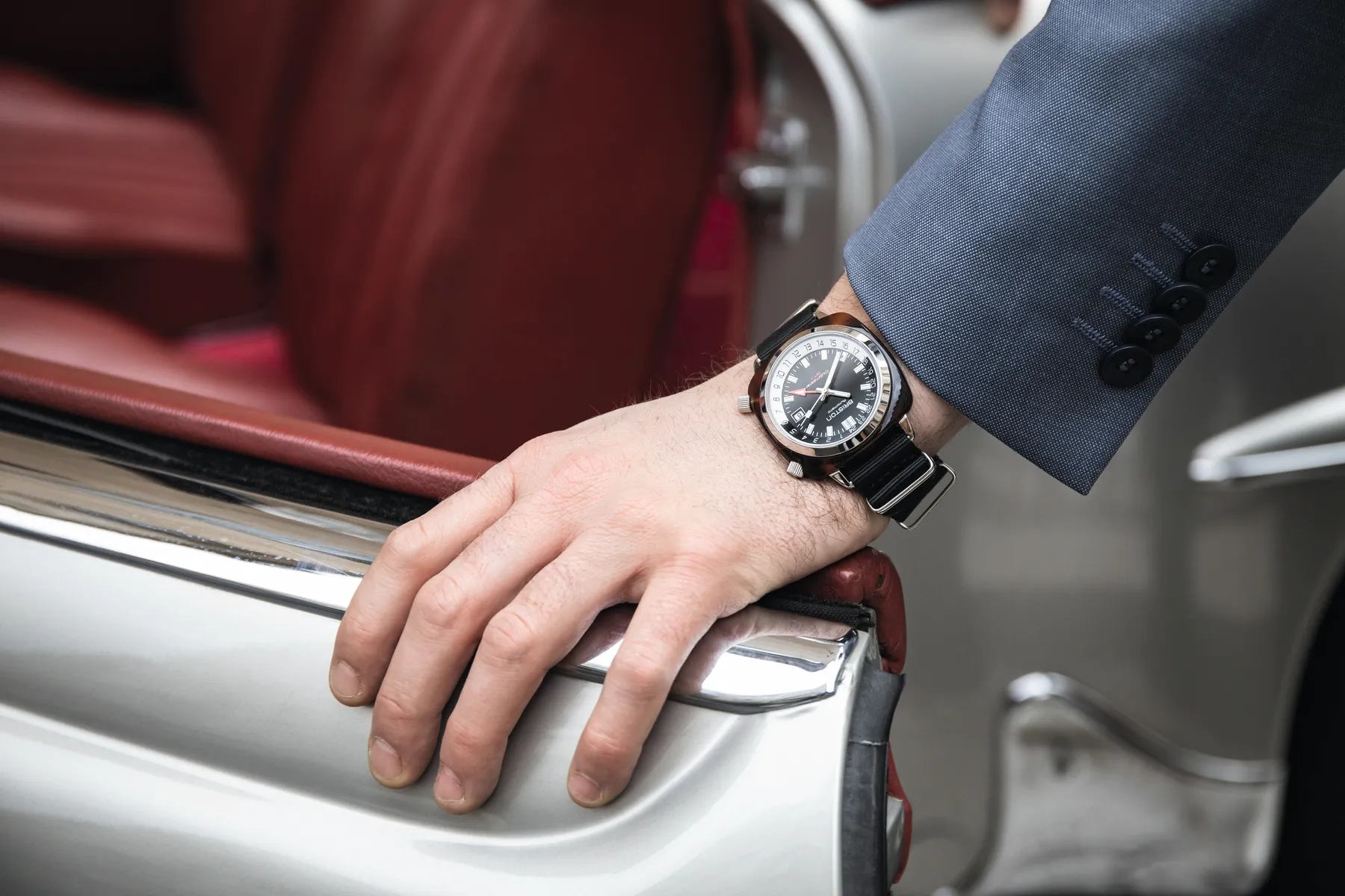 Briston Clubmaster GMT worn on the wrist with a tailored jacket