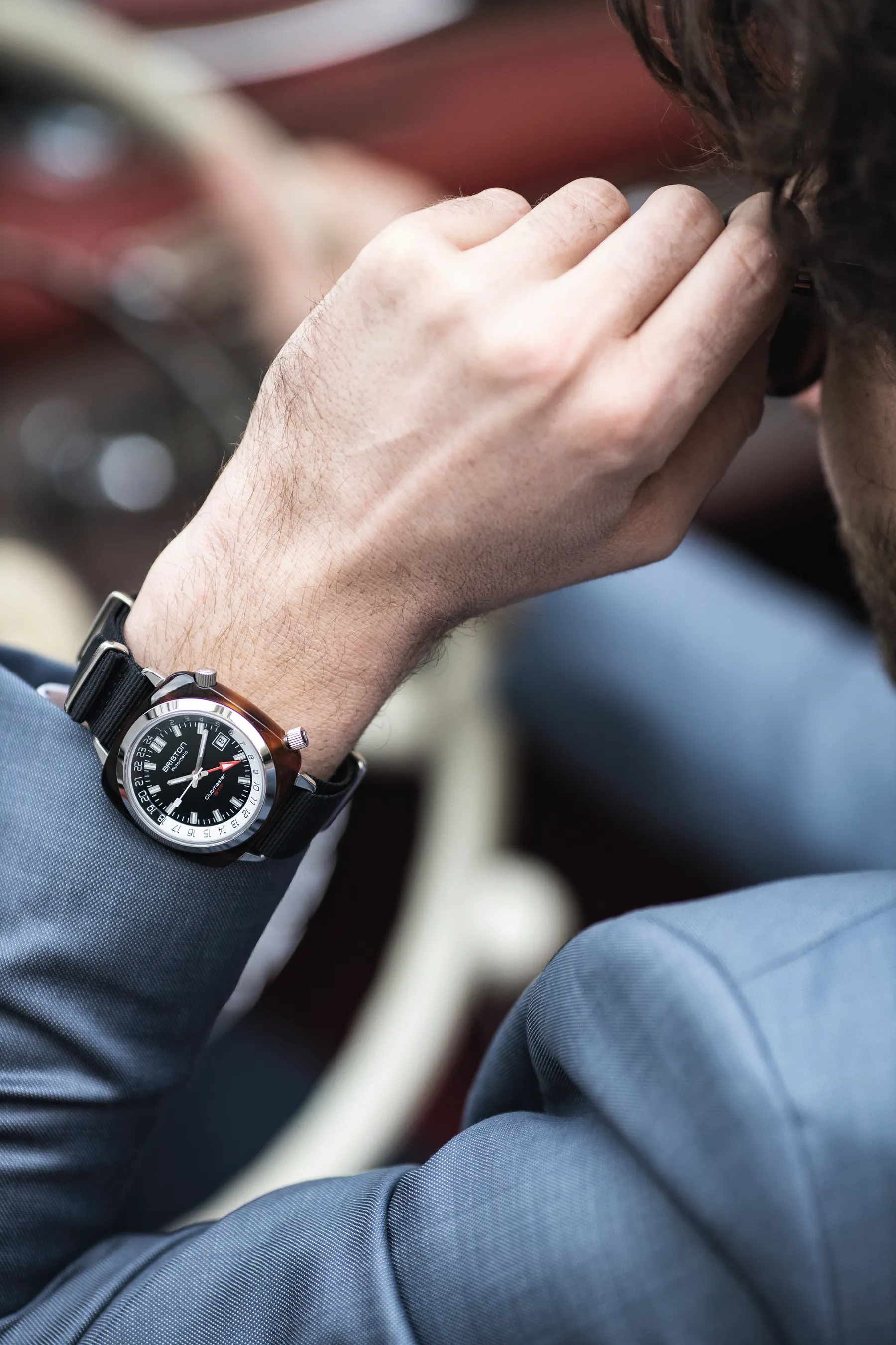 Briston watch photographed beside a vintage film camera on a wooden table