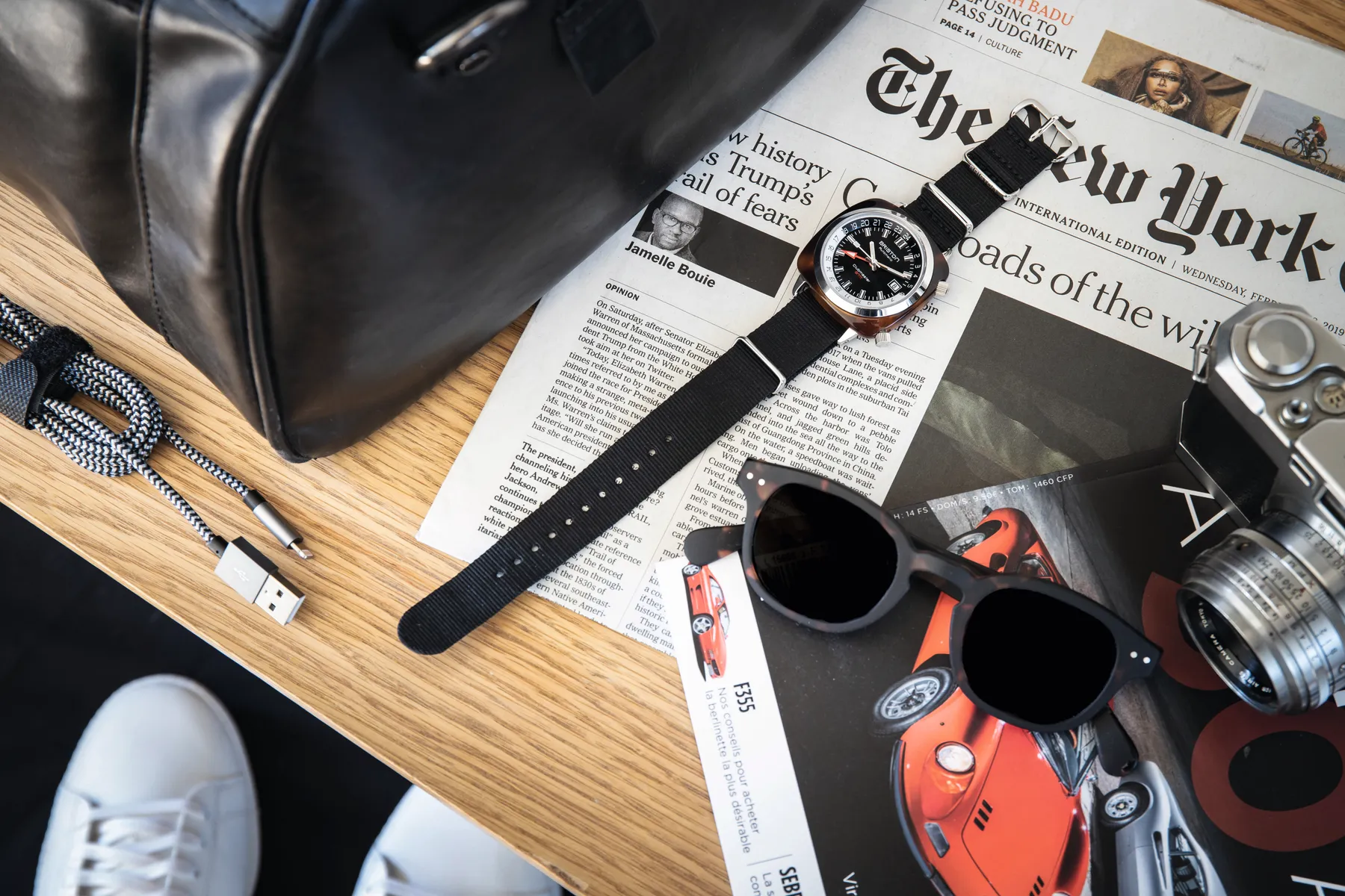 A wristwatch, spare straps and tools laid out on a newspaper