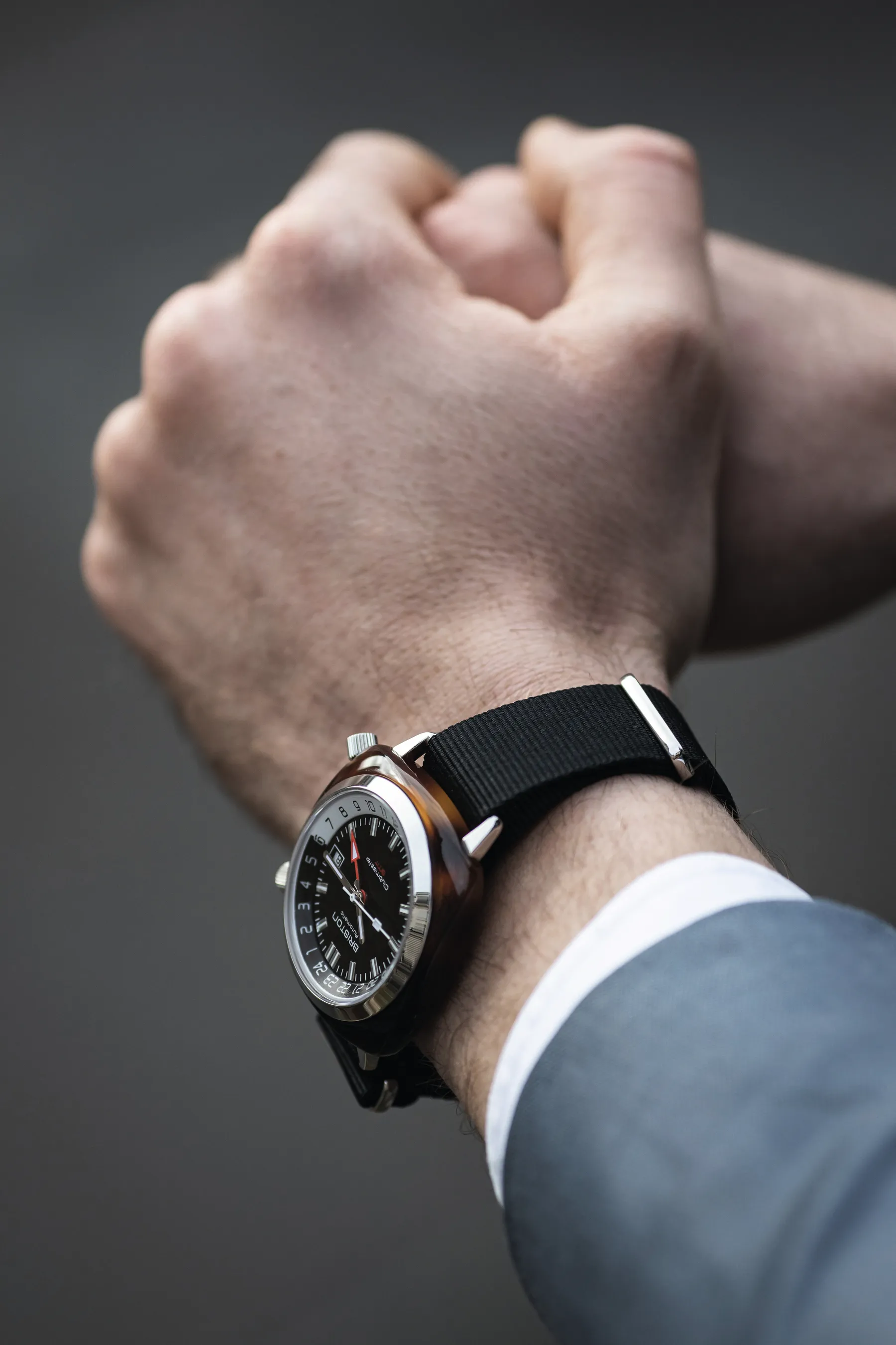 Briston Clubmaster GMT worn with a suit cuff while carrying a leather holdall