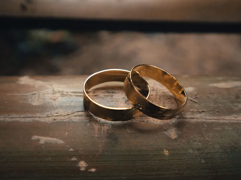 Two gold rings overlapping on a wooden surface
