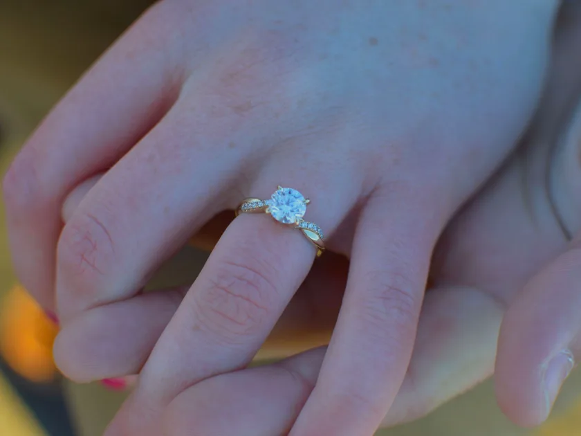A diamond engagement ring resting on a dark surface