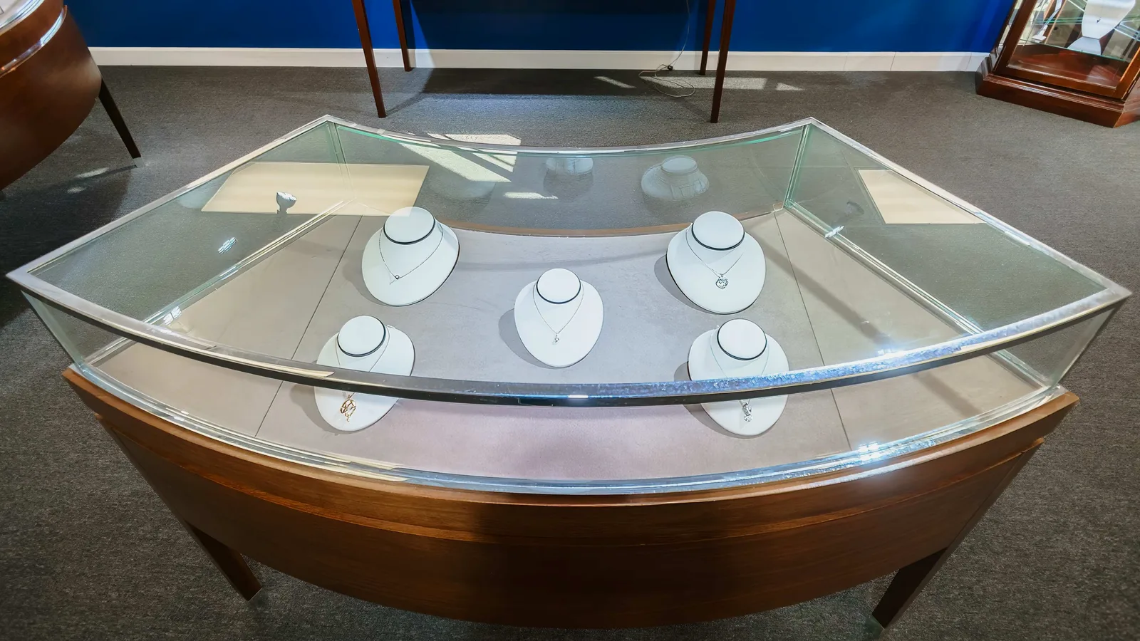 Diamond pendant necklaces displayed on stands inside a lit jewelry case