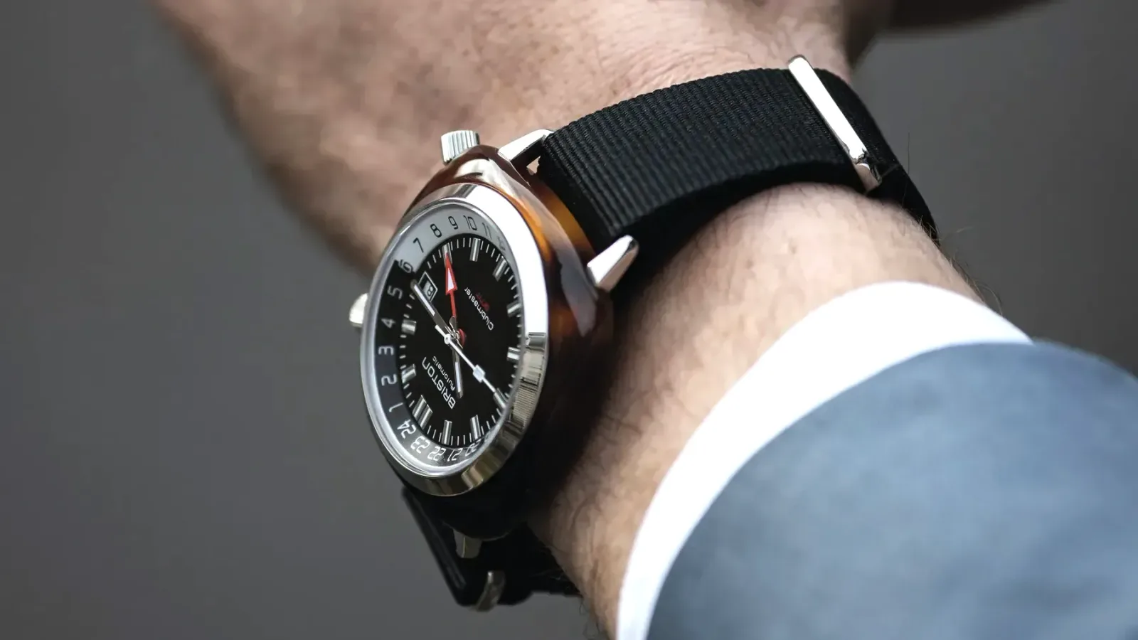 A Briston watch on a black NATO strap worn at the cuff