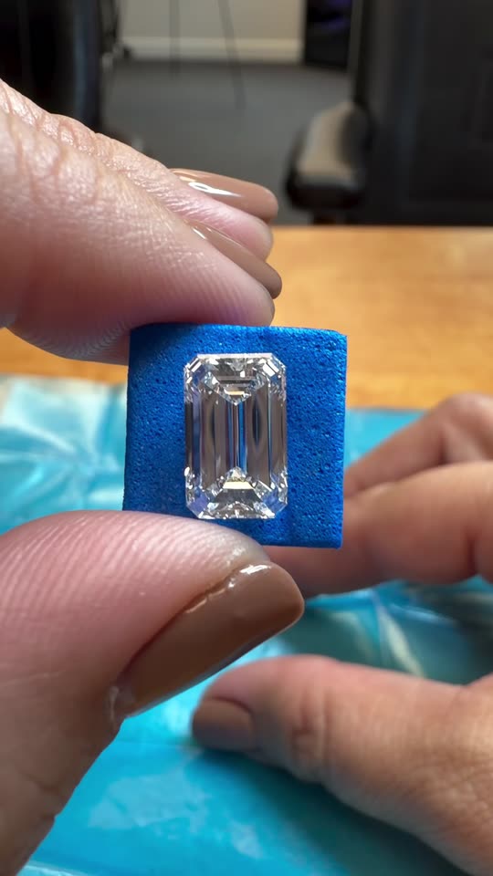 A loose emerald cut diamond unwrapped from its parcel paper