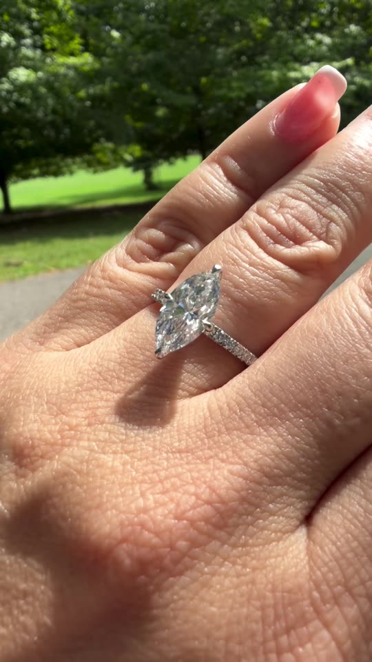 A marquise diamond engagement ring worn on the hand outdoors