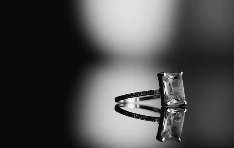 A radiant cut solitaire ring on a dark reflective surface