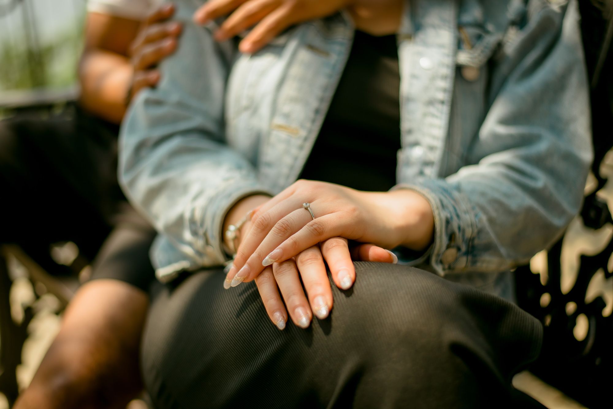 A couple sitting close together, an engagement ring on her hand