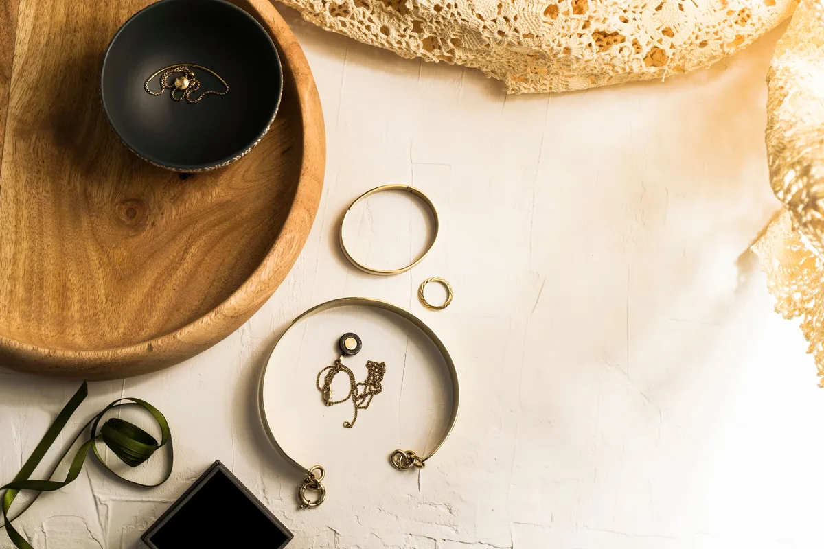 Gold bangles, a ring and fine chains gathered on a wooden tray with lace