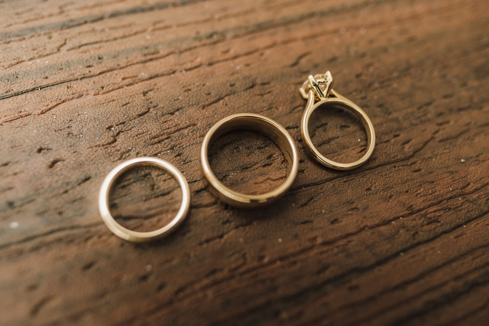 Three gold rings of different ages resting together on dark wood