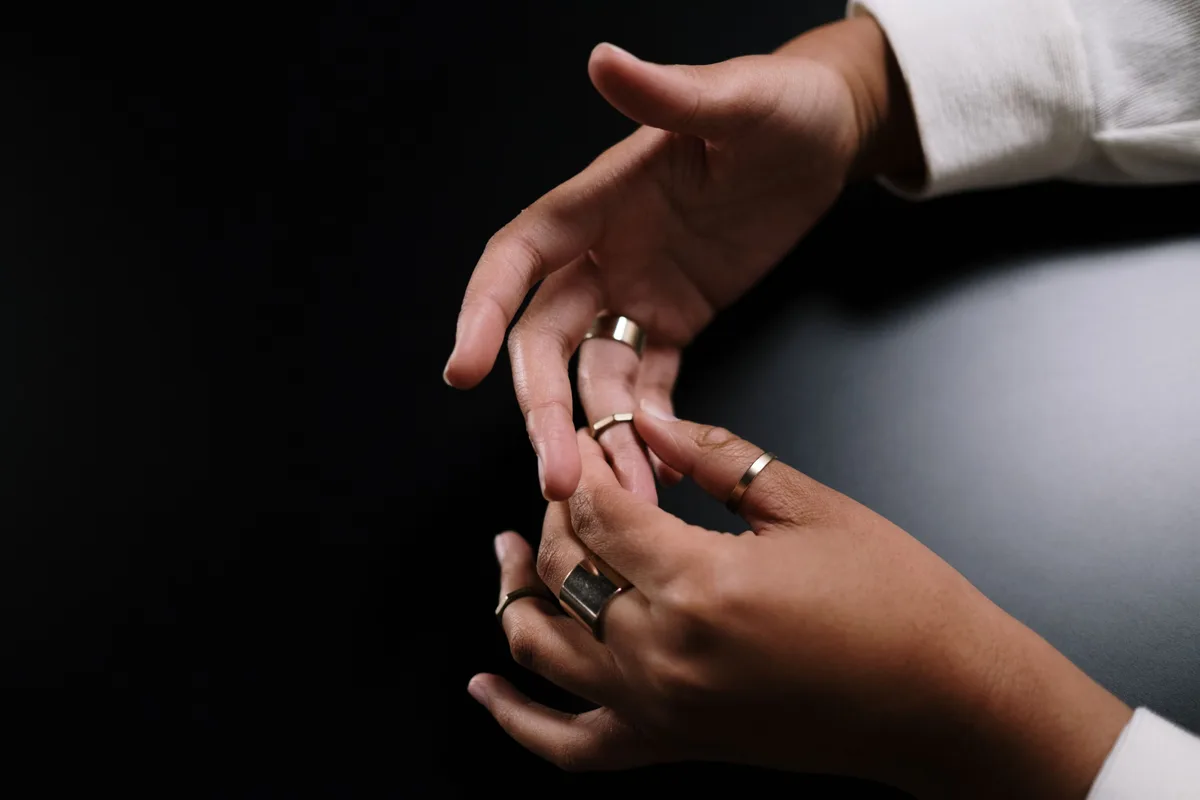 Two hands turning a gold band on a finger to check how it sits