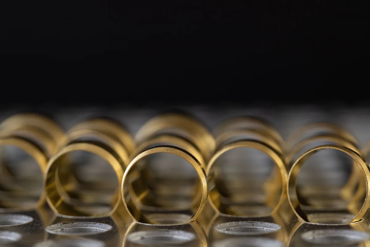 A row of plain gold bands standing on a reflective surface