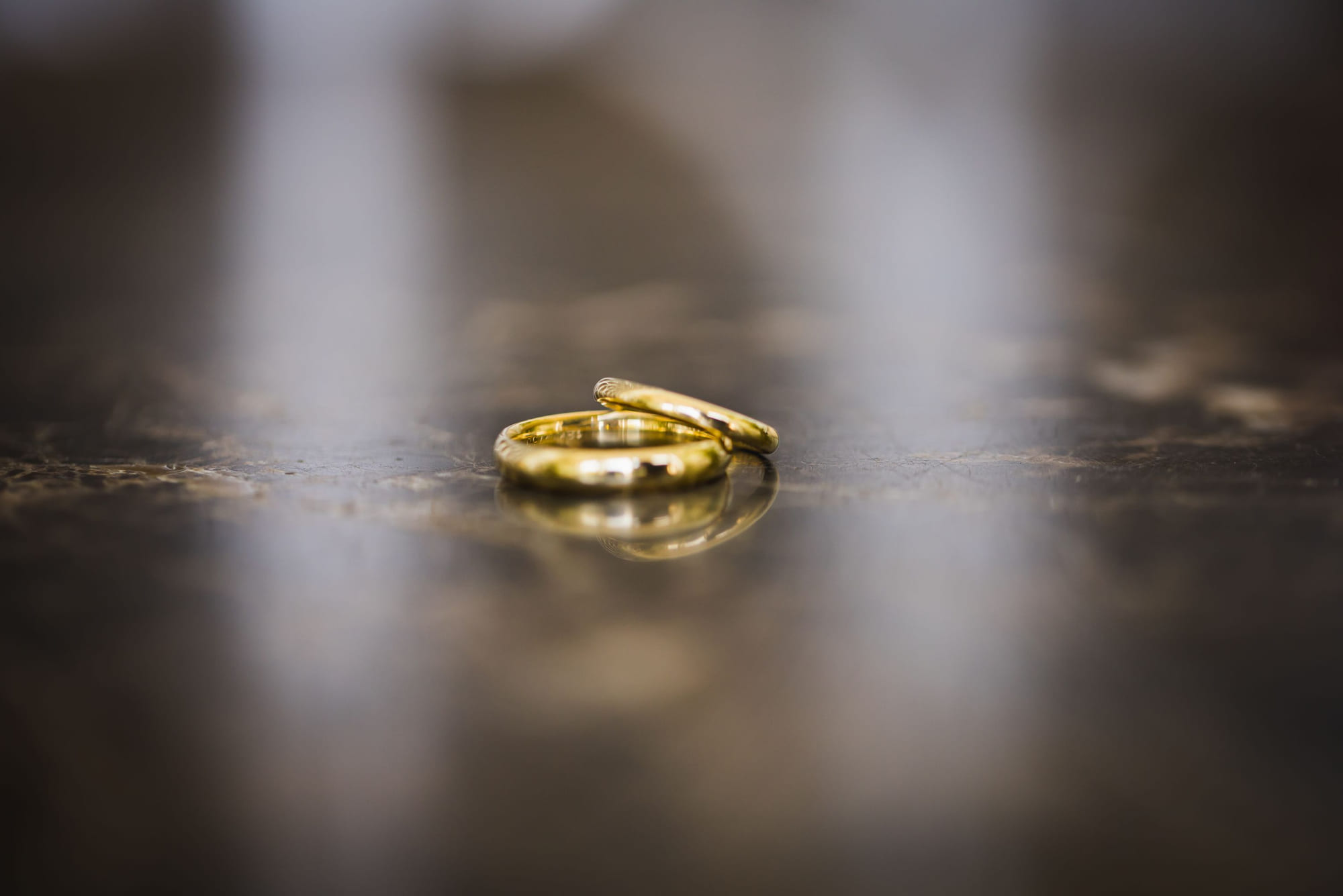 Two gold wedding bands resting on a polished stone surface