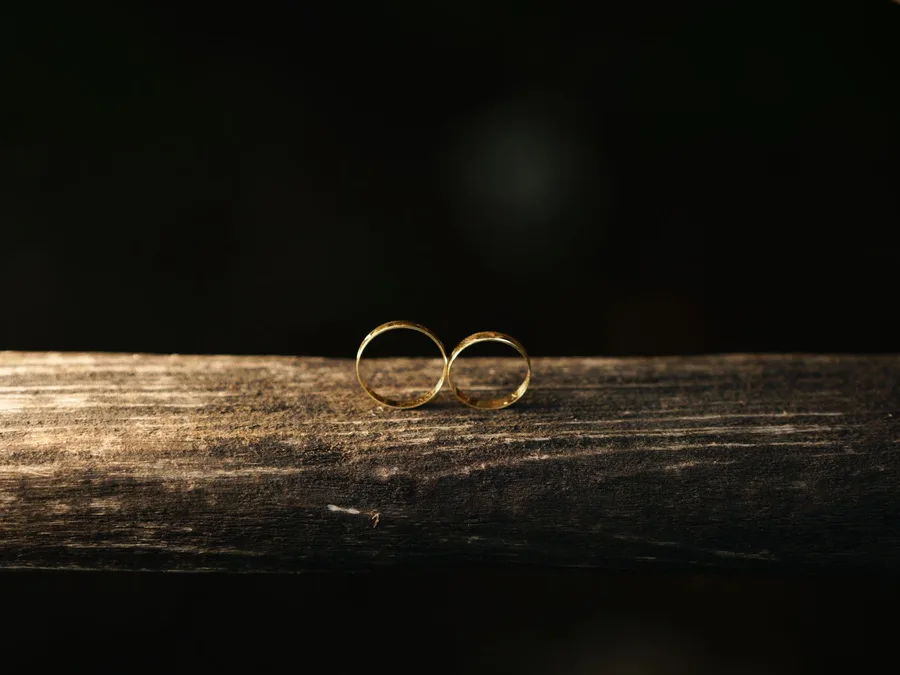 Two gold wedding bands resting together on wood